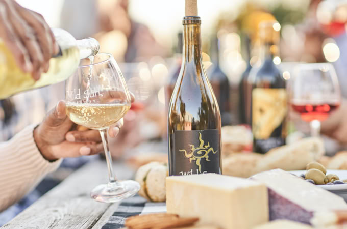man pouring a glass of white wine outside at wild sun winery